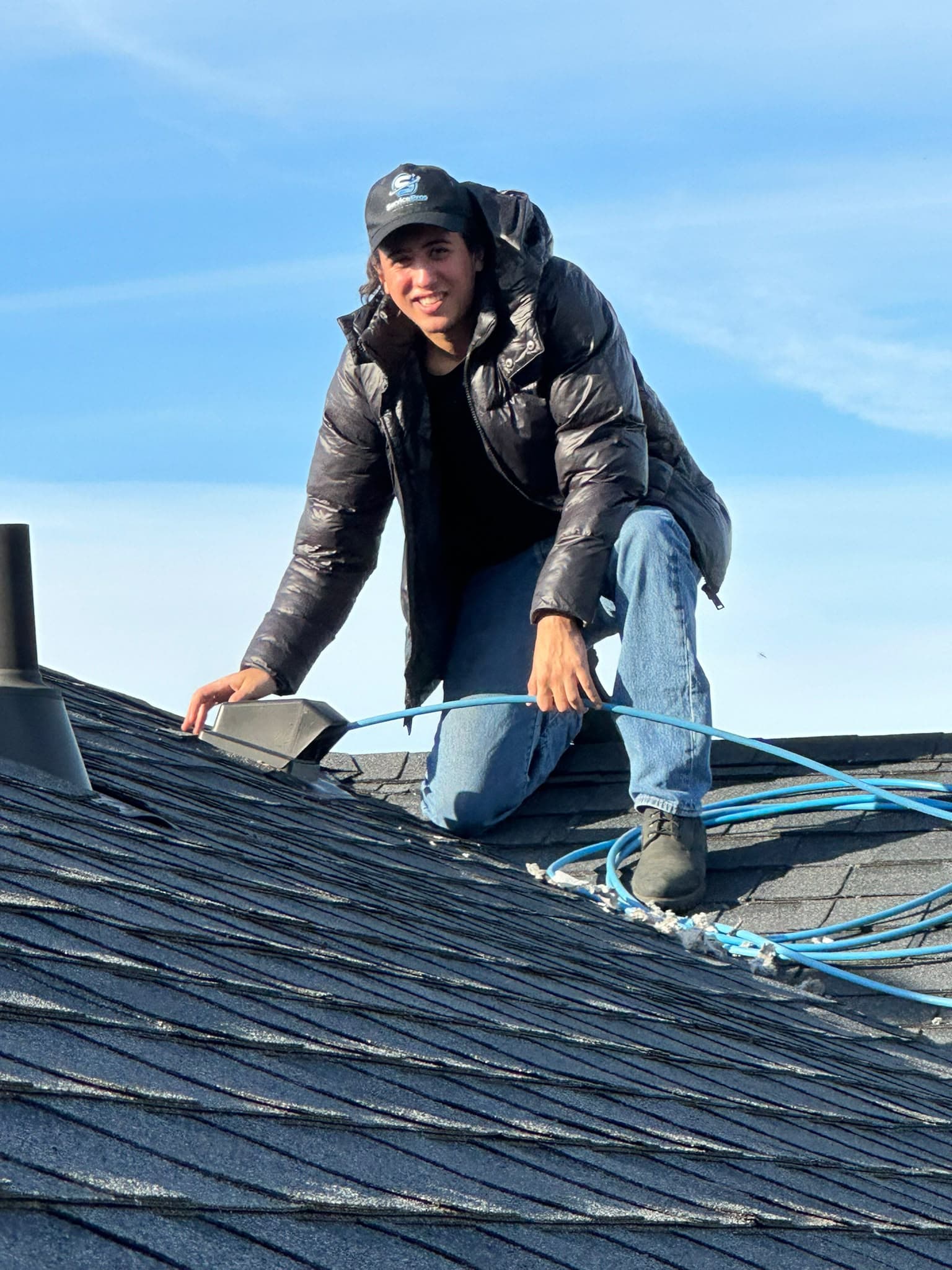 ServicePros technician using a blue hose at a rooftop vent